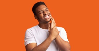 Toothache Concept. Portrait of black man touching cheek with abscessed tooth, panorama with copy space