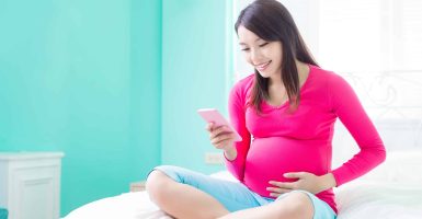 beauty pregnancy woman use phone and smile happily on the bed