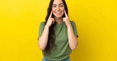Young caucasian woman isolated on yellow background smiling with a happy and pleasant expression